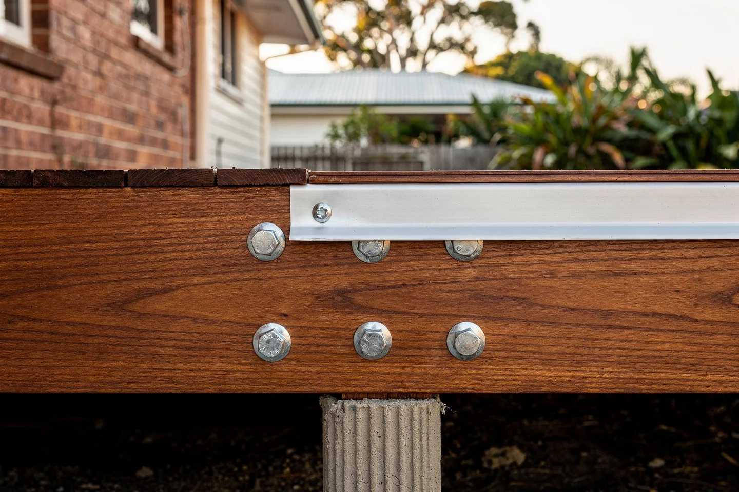 A hardwood ledger board bolted to a coastal weatherboard wall with clean step-flashing above and lapped over the ledger